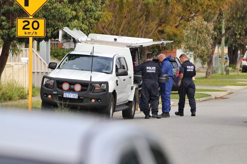 Three police officers in forensic uniforms standing next to a white unmarked police van on a suburban street.