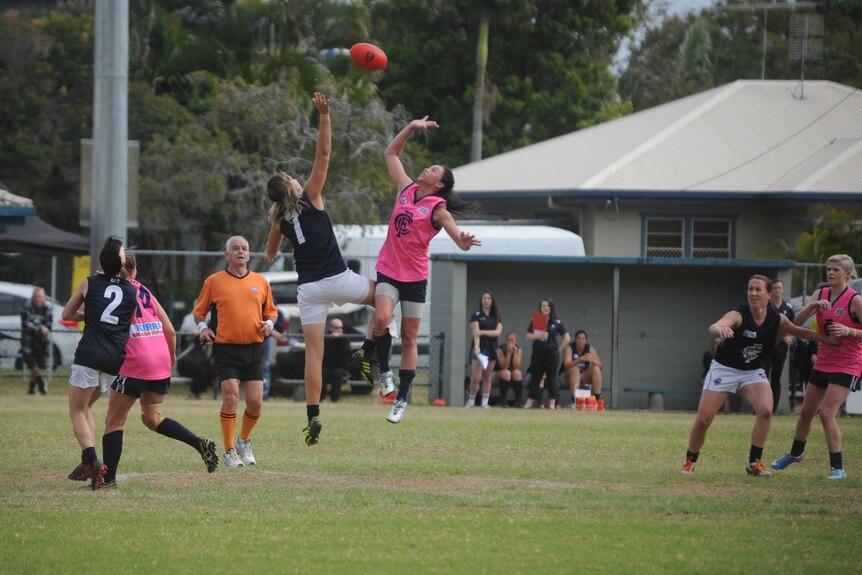 Two women's AFL players jump for the ball in a ruck contest.