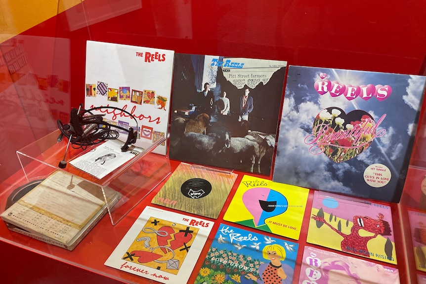 A display of vinyl records and cassettes by The Reels, along with a headset and microphone