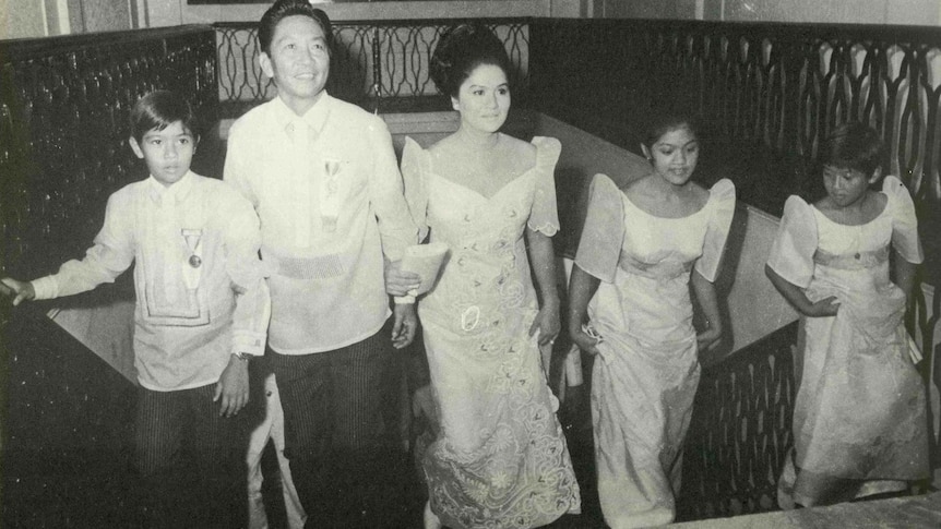 A black and white photo of a young Imelda and Ferdinand Marcos walking up a staircase with their son and two daughters