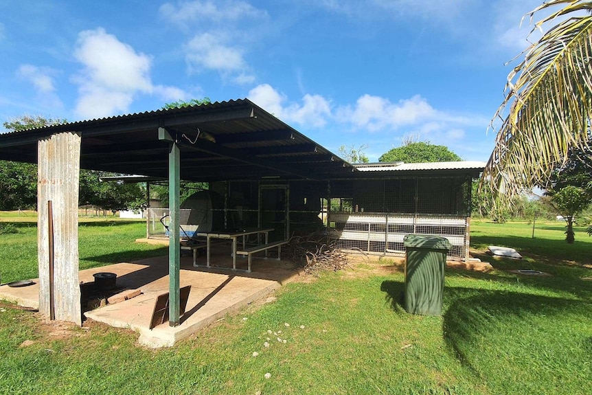 A makeshift home made out of a fenced areas on a concrete slab.