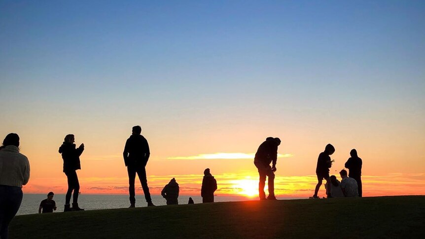 Silhouettes of people on a hill at last light.