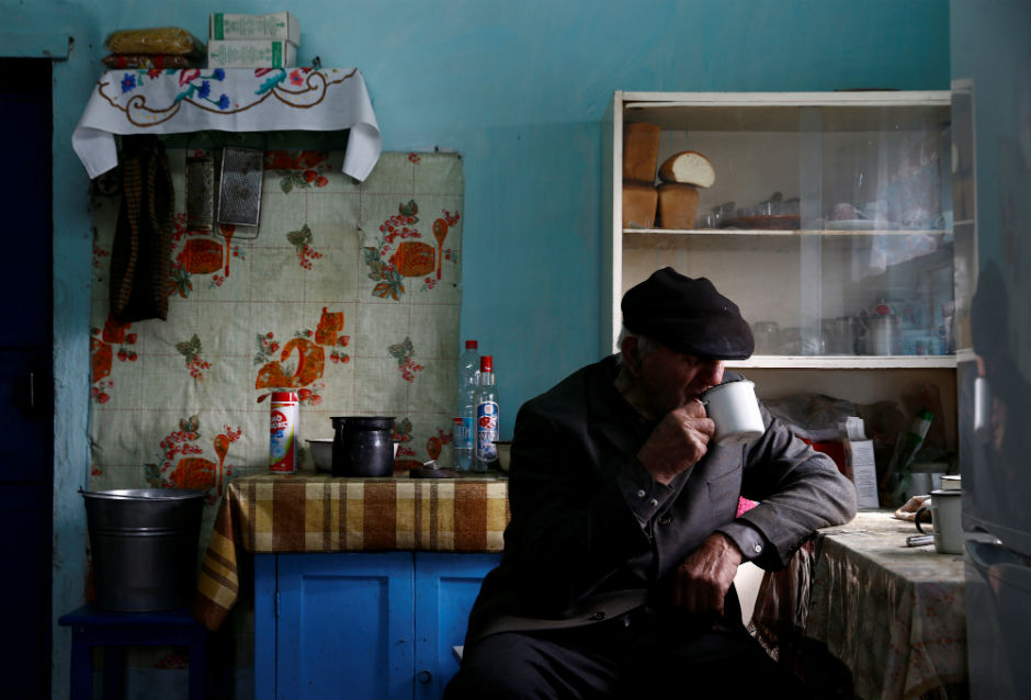Ivan Shamyanok sips a cup of tea as he sits at a table in his home.