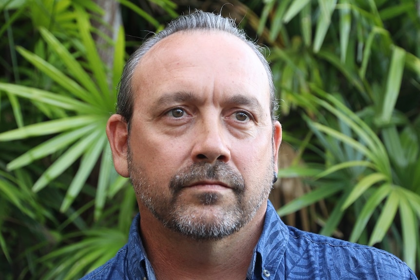 Close up photo of Victor Steffensen with green palms in background.