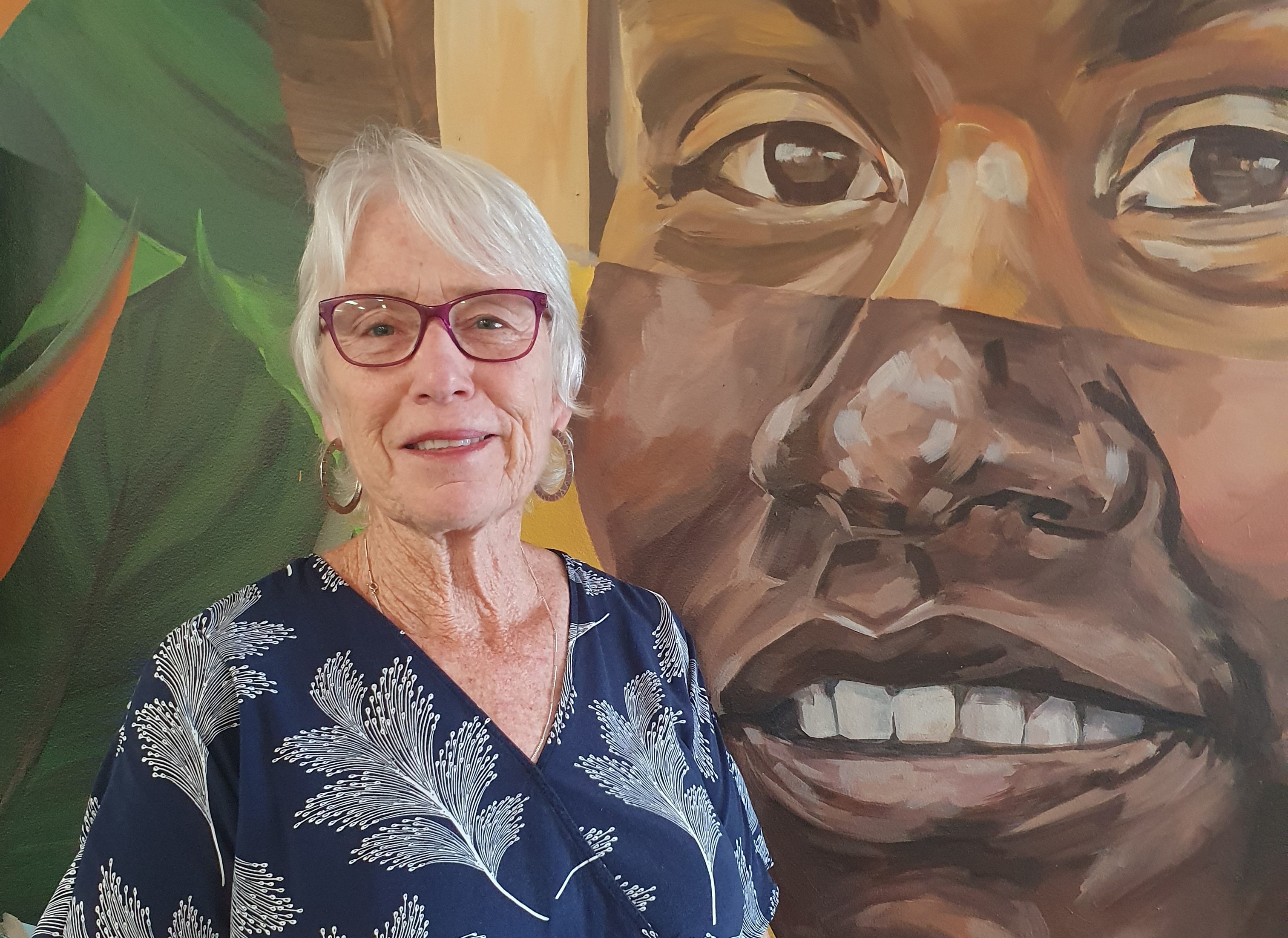 close up head shot of Gisela Hansson with colourful mural behind her