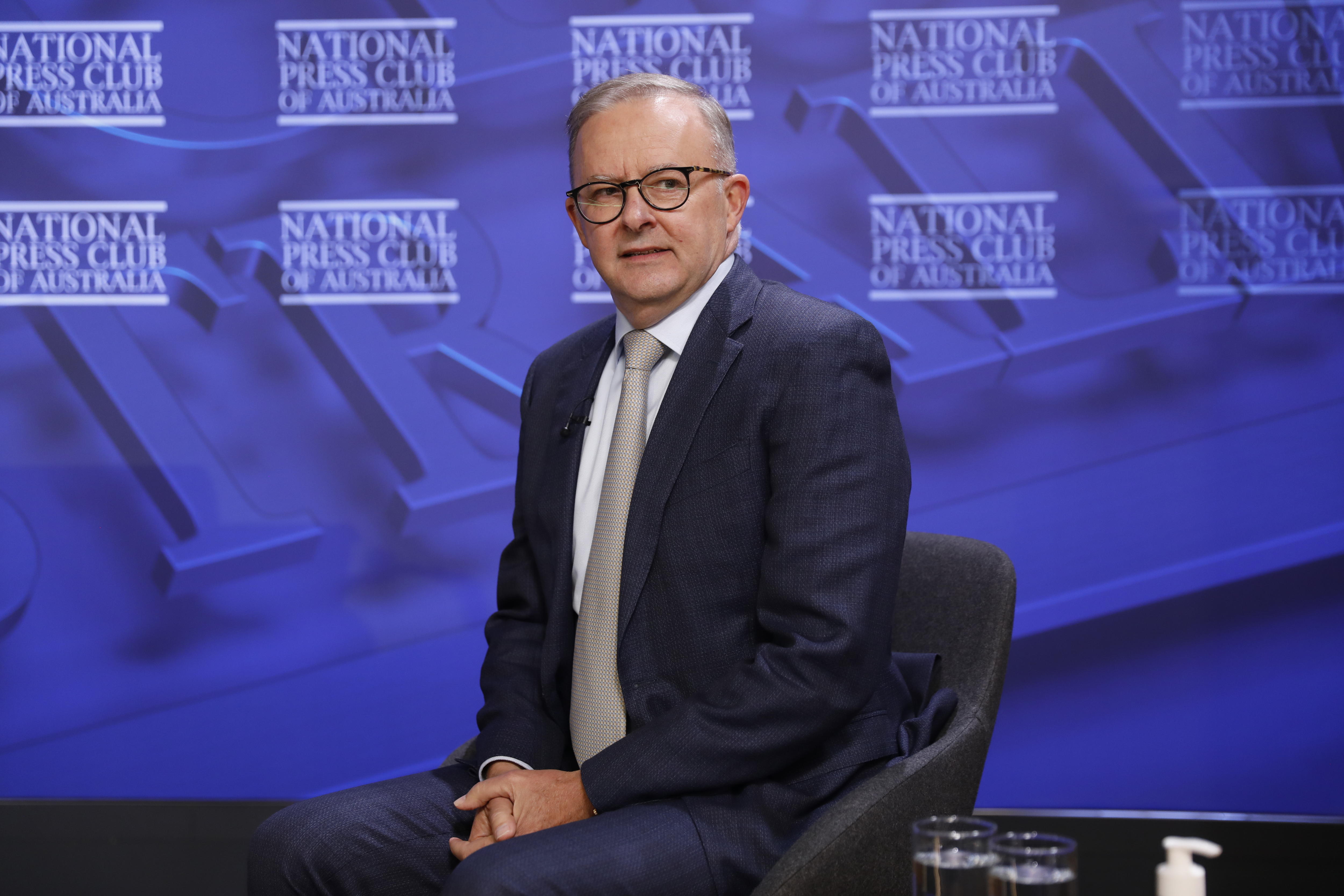 Anthony Albanese sits on a stage with National Press Club branding behind him