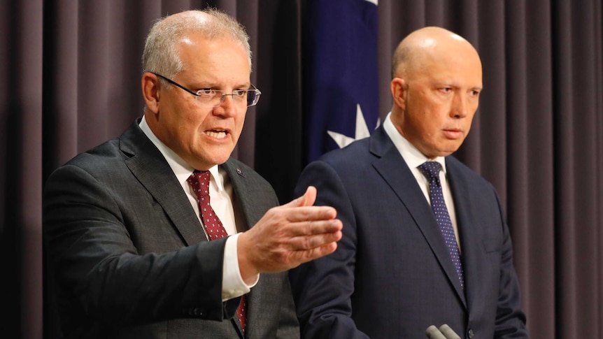 Scott Morrison points while standing alongside Peter Dutton at lecterns. An Australian flag is behind them