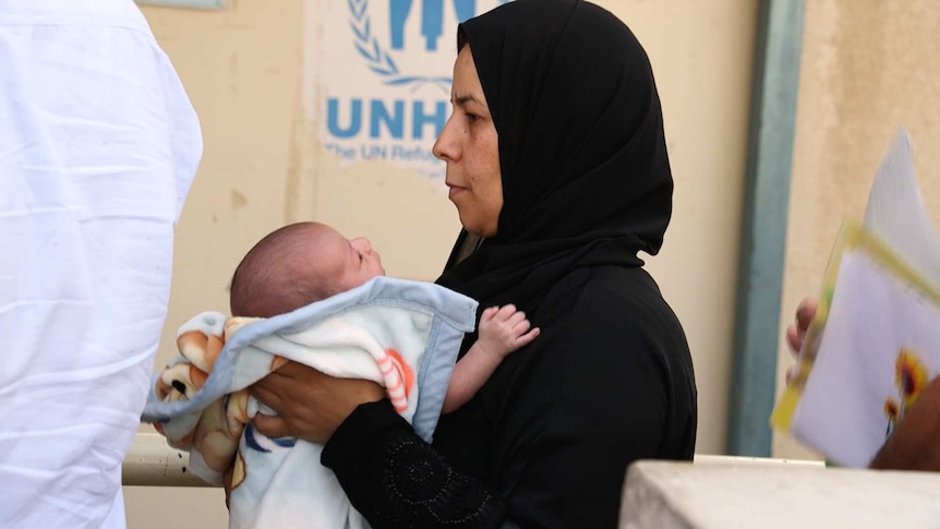 Syrian refugees wait in line at the UNHCR in Amman, Jordan.