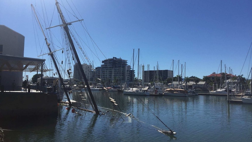 Historic tall ship Defender underwater in Townsville, with just its mast showing.