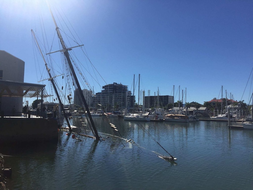 Historic tall ship Defender underwater in Townsville, with just its mast showing.