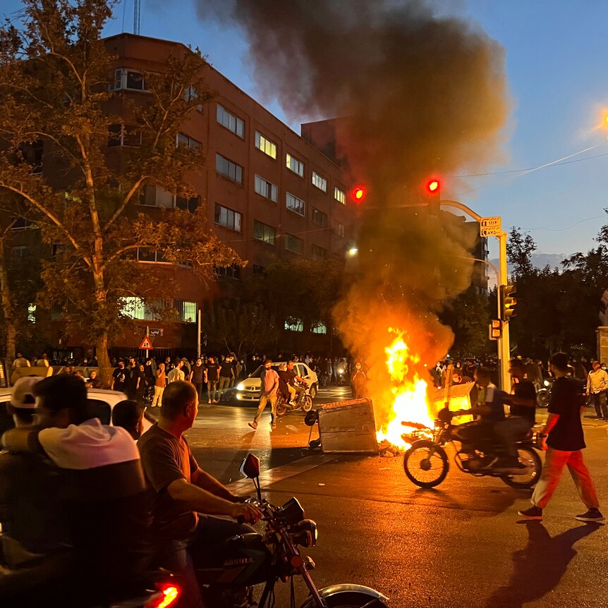 A police motorcycle and a trash bin are burning during a protest in Iran
