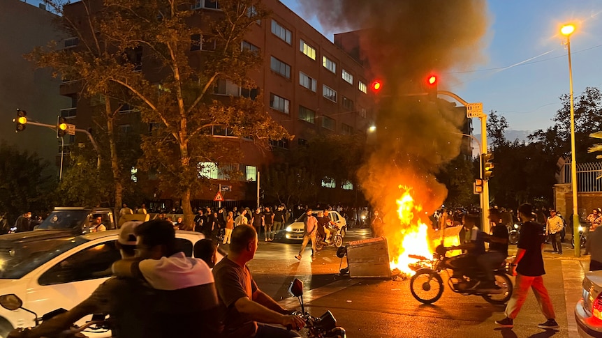 A police motorcycle and a trash bin are burning during a protest in Iran