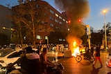 A police motorcycle and a trash bin are burning during a protest.