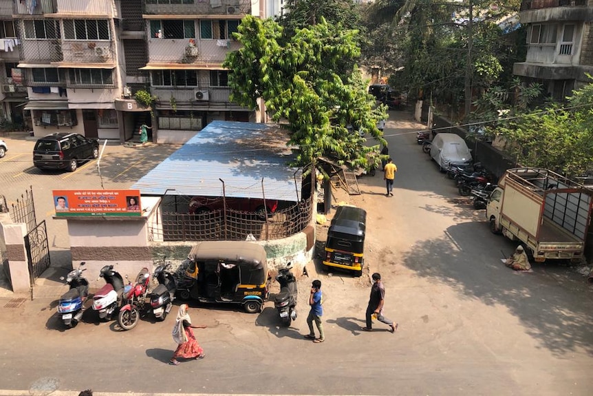 A few people walk down the street in India.