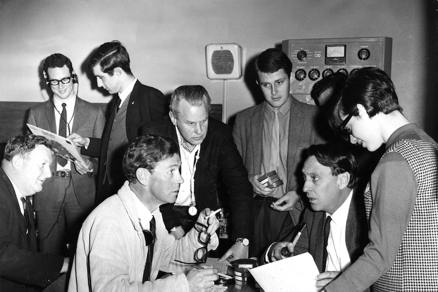 Producers and reporters working on AM stand together in a small room in 1967.
