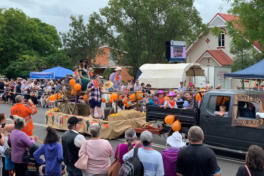 Children sit on a float that is being pulled by a ute down the main street of Gayndah during the orange festival