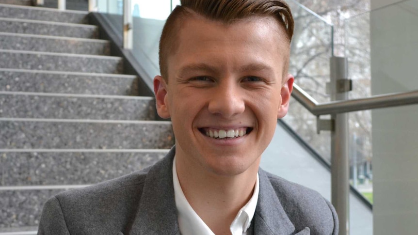 16-year-old Josh Brnjac sits on steps and smiles for the camera.