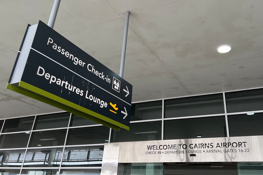 A sign directing people to passenger check-in and the departures lounge at an entrance to the Cairns Airport domestic terminal.