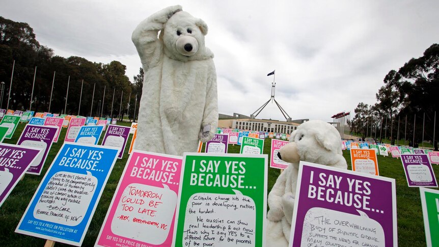 Carbox tax supporters dressed as polar bears pose in front of placards outside of Parliament House.