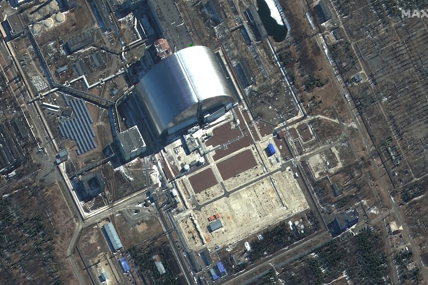 A bird's eye view of an industrial area with a large silver cylindrical structure.