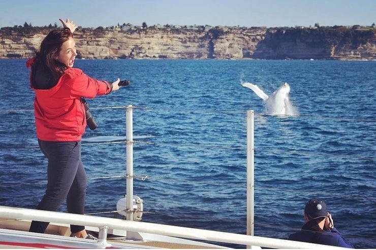 a woman on a boat with whales in the background