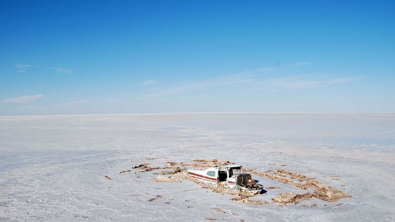The wreckage of a light plane lies embedded in the surface of Lake Eyre