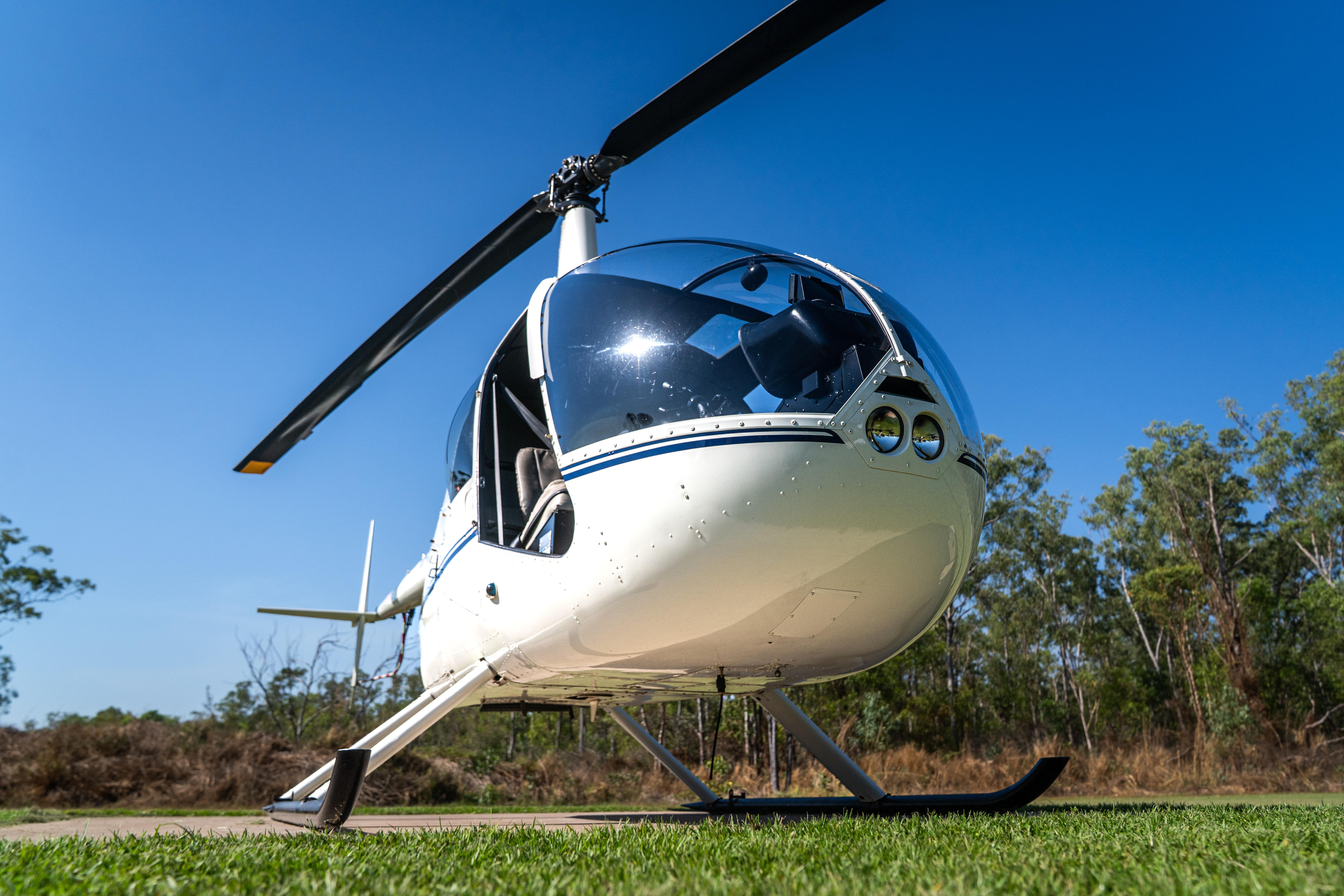 A chopper shot from below, it is parked on green grass and a blue sky can be seen in the background.