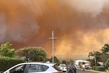 Smoke blankets a suburban street in Tathra.