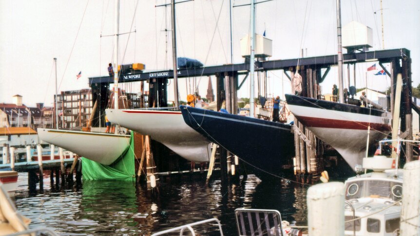 Australia II (left) with its keel hidden behind coverings at the dock in Newport.
