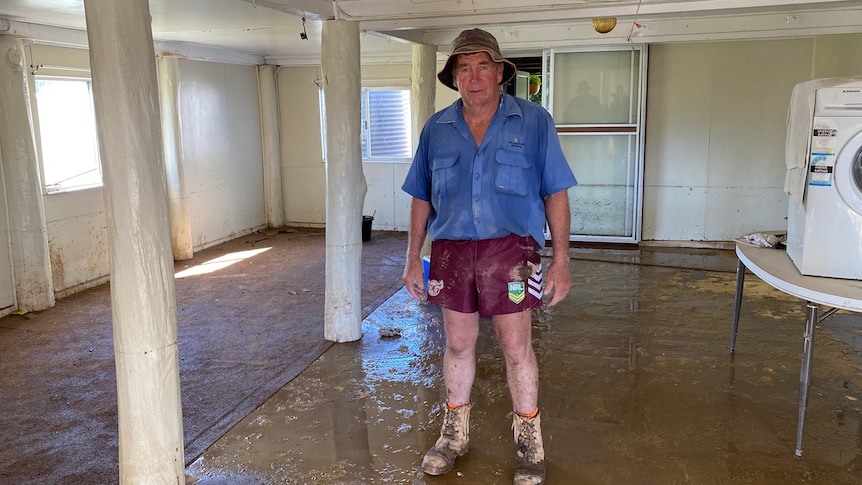 A man in a muddy empty house looking at the camera. 