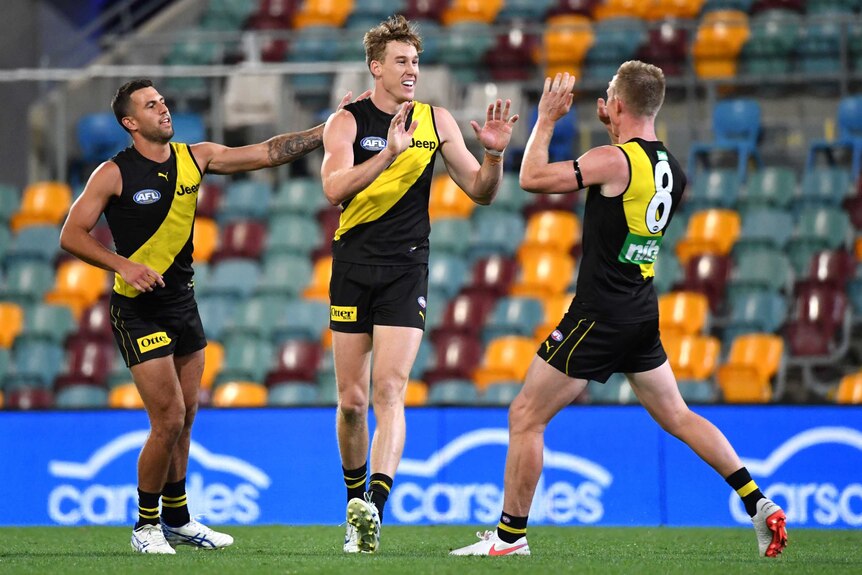 Two AFL teammates move to high five after a goal for their side.