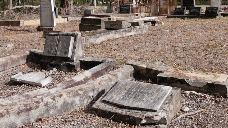 A graveyard where some headstone are shown lying flat on the graves.