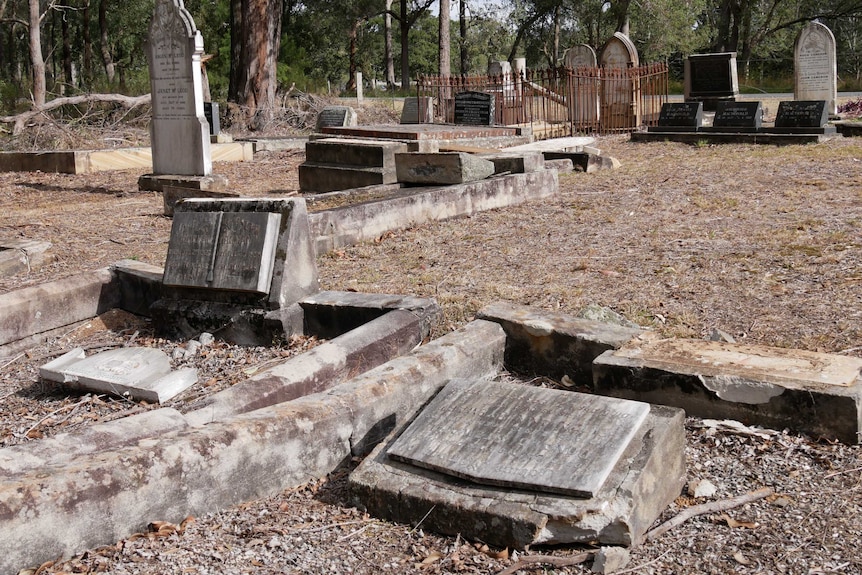 A graveyard where some headstone are shown lying flat on the graves.