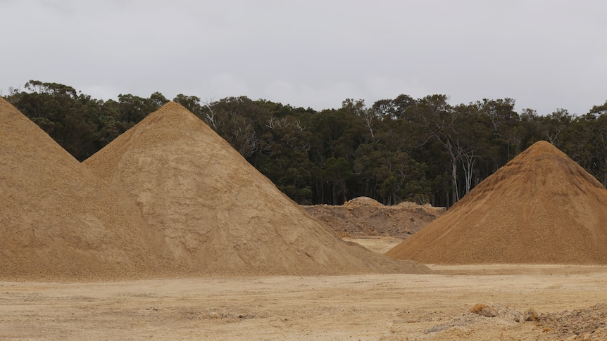 A wide shot with three piles of sand in the foreground.