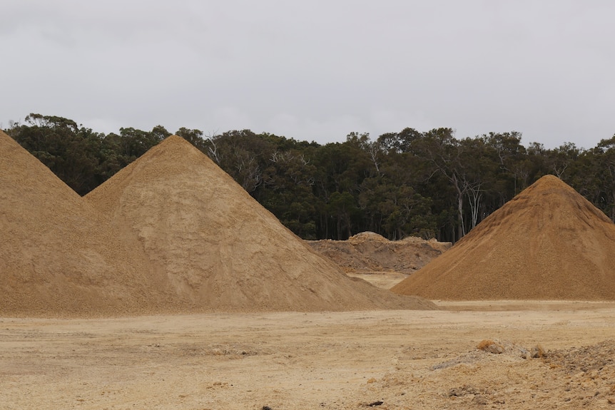 A wide shot with three piles of sand in the foreground.