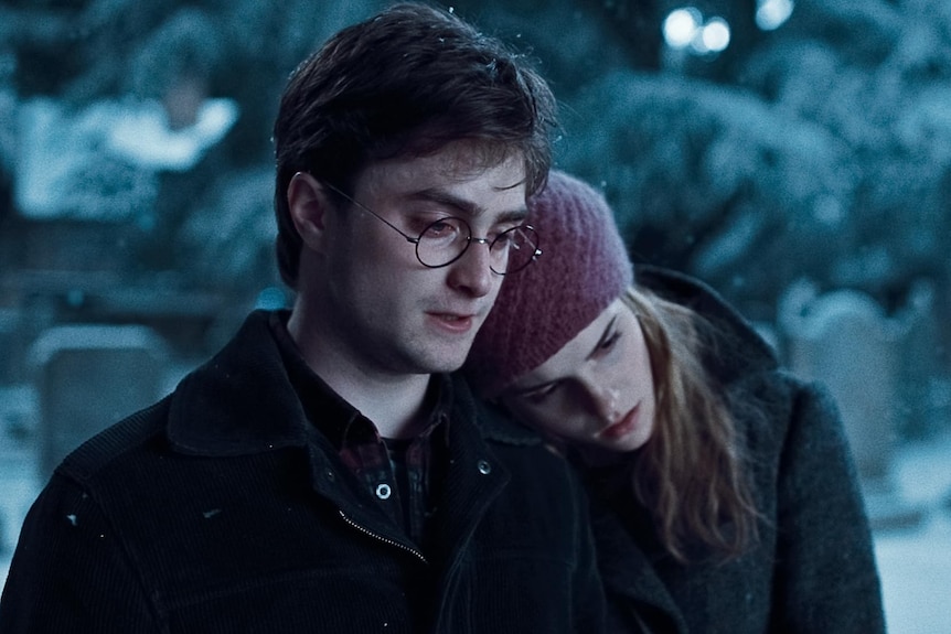 Harry cries in a cemetery as it snows as Hermonie leans her head on his left shoulder.
