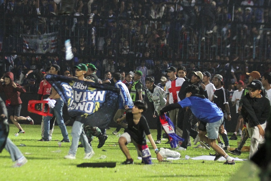 Fans run onto a field with flags and banners.
