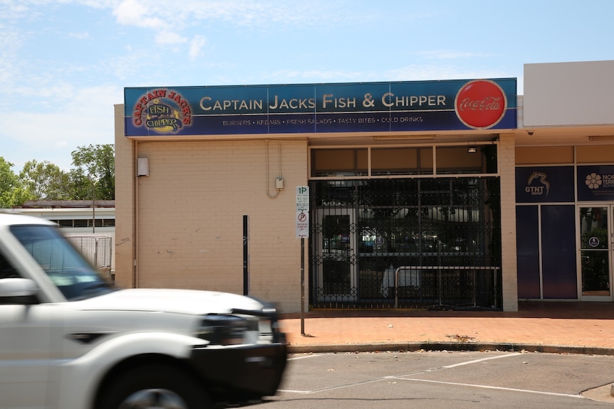 A shopfront with a closed metal gate over the doors.