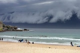 People go about their day on Bondi Beach in Sydney as a storm front moves towards the city.