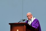 Pope Francis, dressed in purple, stands at a podium as he delivers his mass in Ecatepec.