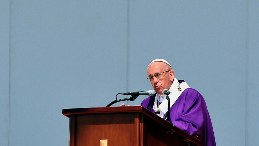 Pope Francis, dressed in purple, stands at a podium as he delivers his mass in Ecatepec.