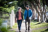 Karl Schurr and Annie McCluskey look at each other while walking down a tree-lined footpath.