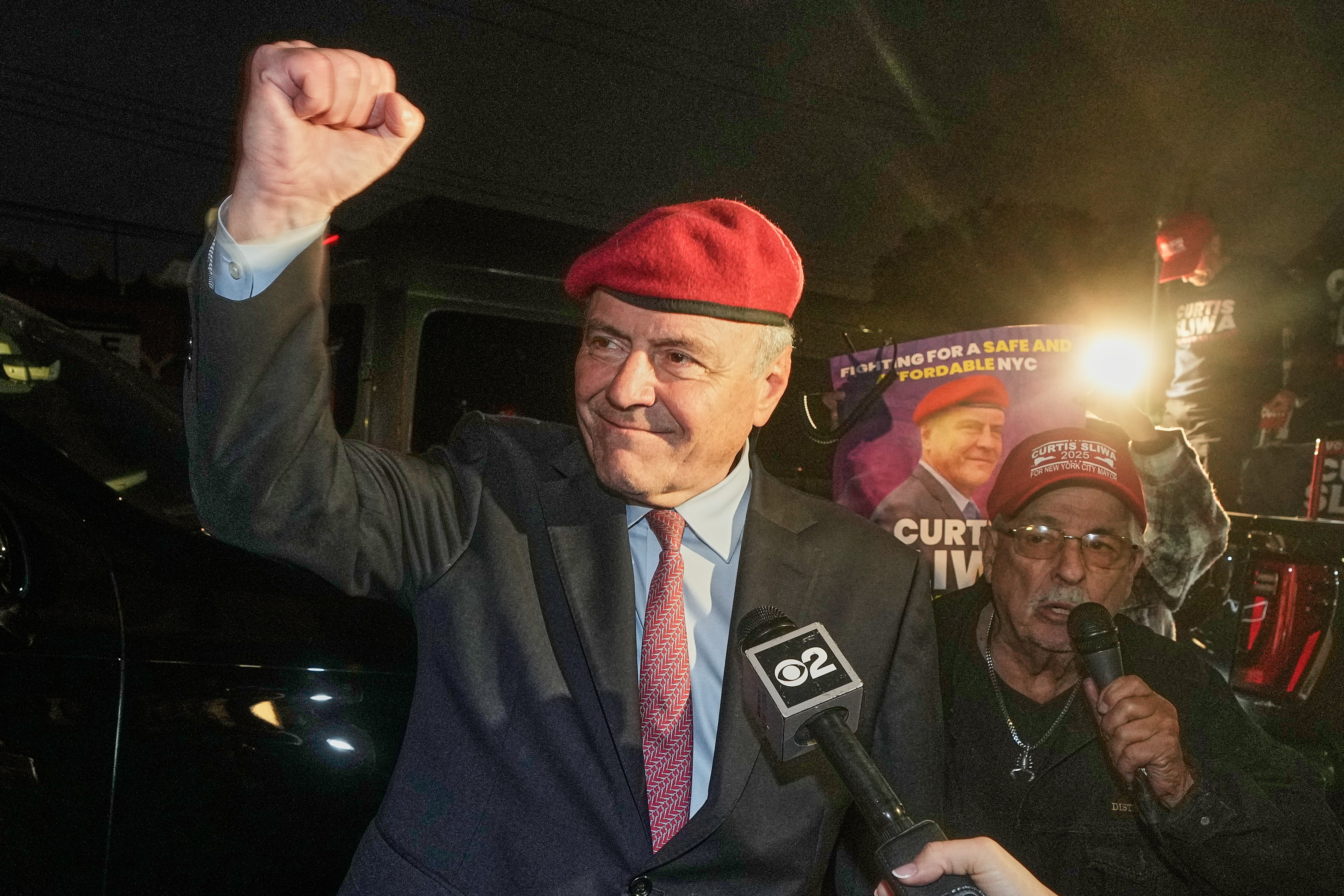 Curtis Sliwa pumping his fist in the air at a rally.