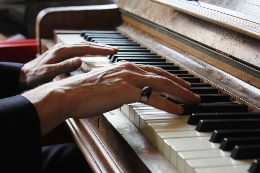 Mr Longo's hands playing the piano in a Hobart cafe.