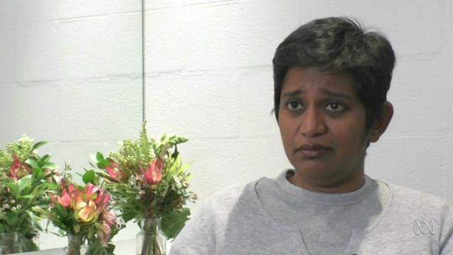 Author Shamini Flint sits beside flowers