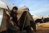 Girls look out of tent at Za'atari refugee camp