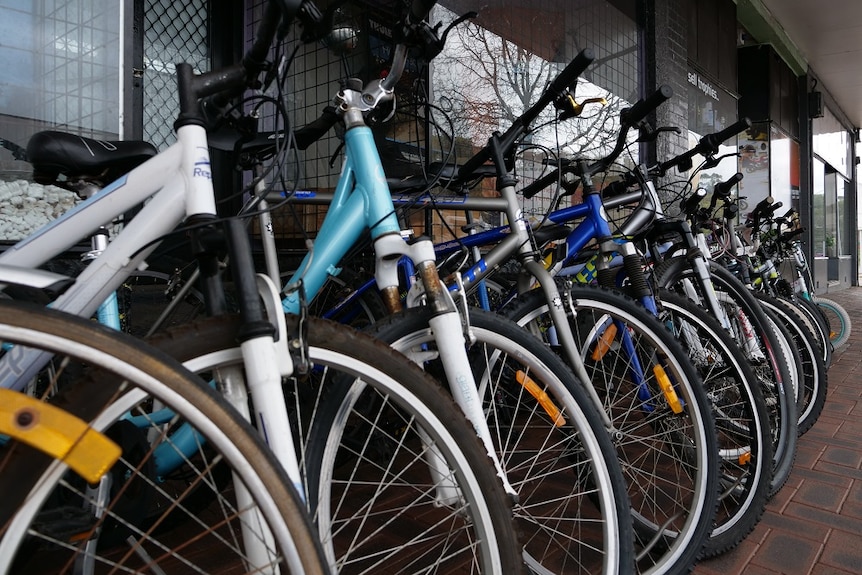 A range of bikes sitting out the front of a shop.