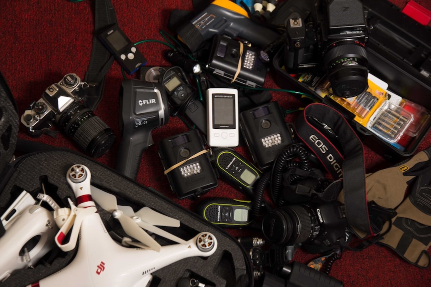 Electrical equipment including a drone, walkie talkies a drone and infra-red detectors lying on carpet