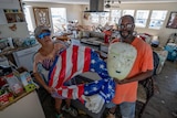Man and woman holding a floatie in a kitchen following a hurricane.