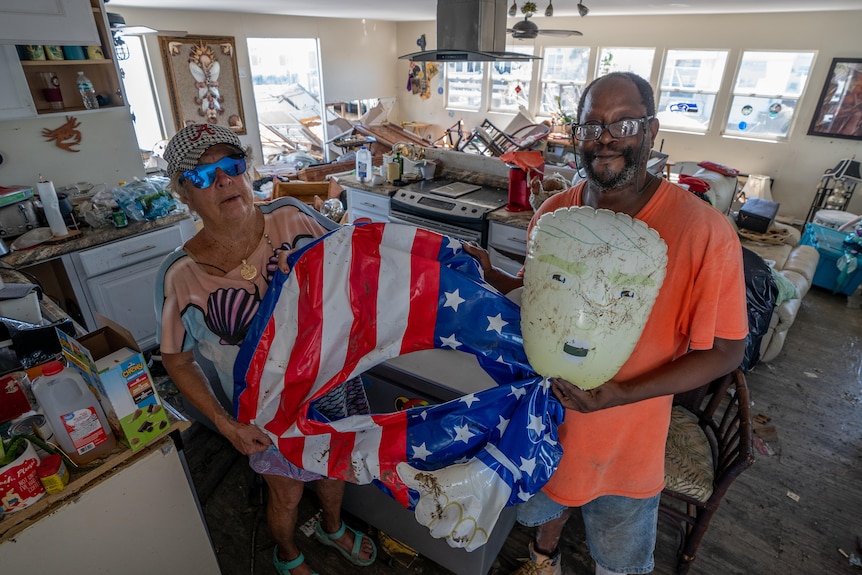 Man and woman holding a floatie in a kitchen following a hurricane.